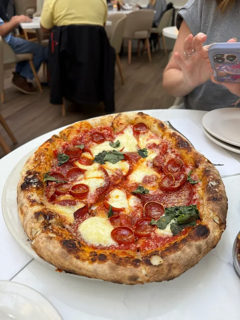 A wood-fired pepperoni and ricotta pie with blistered crust on a white plate at Brewster's in New Buffalo