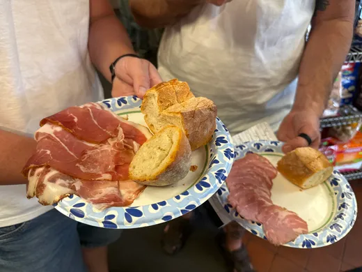 Two plates of Freddy's bread, mortadella and cheese held up in the deli aisle