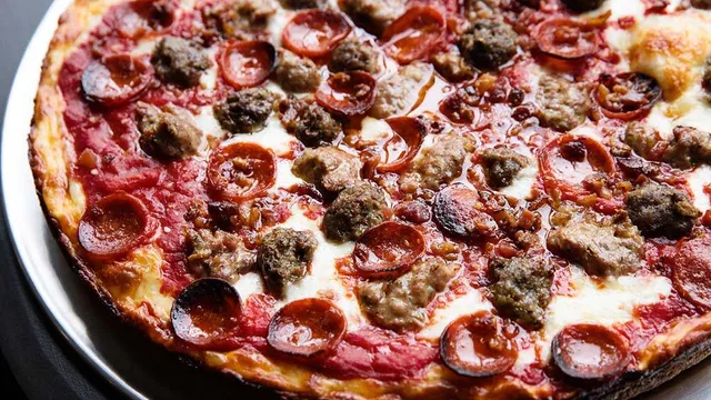 Close-up of a George's Deep Dish pie loaded with sausage chunks and pepperoni, crust edge browned and crisp