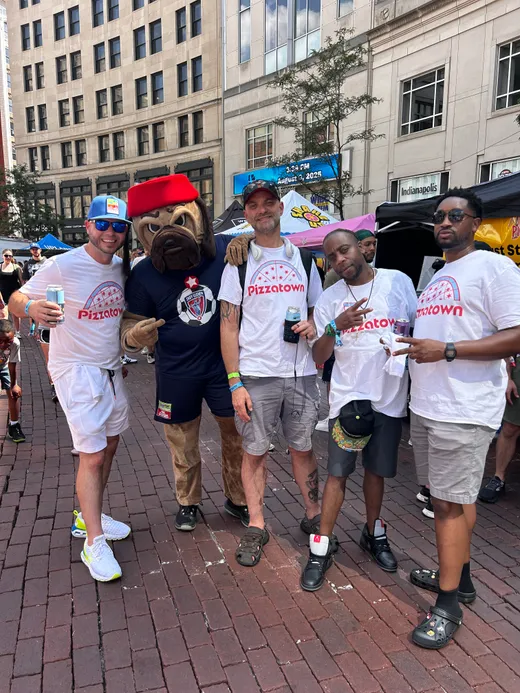 The crew with drinks in hand working a sunny festival street in Indianapolis