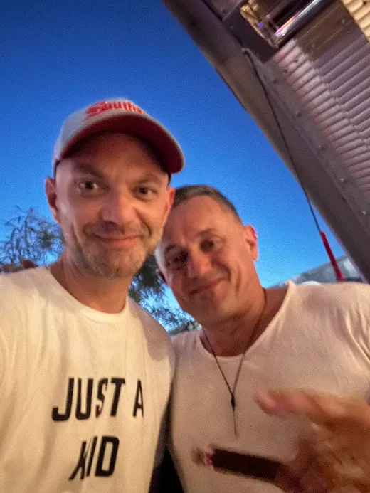 A slice scout grinning in a selfie with Mario at a nighttime pizza event