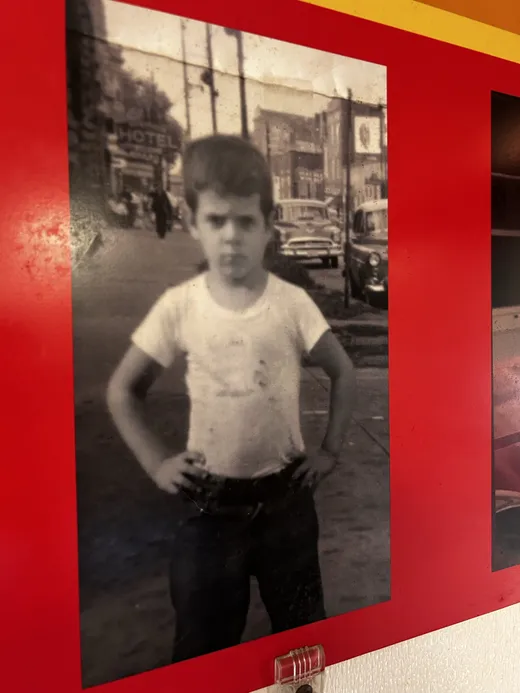 A framed black-and-white photo at Pat's: a kid with hands on hips on an old Chicago street