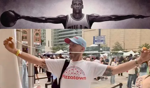 A slice scout in a Pizzatown shirt stretching a cheese pull wide in front of the Michael Jordan wings mural