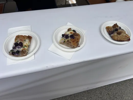 Three tasting squares of Bonci blueberry pizza on little white plates