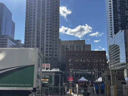 The Pizza City Fest entrance flanked by River North towers on a blue-sky day