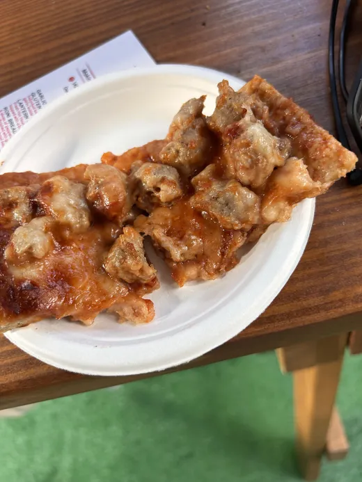 A sausage-heavy square of Chicago classic on a paper plate
