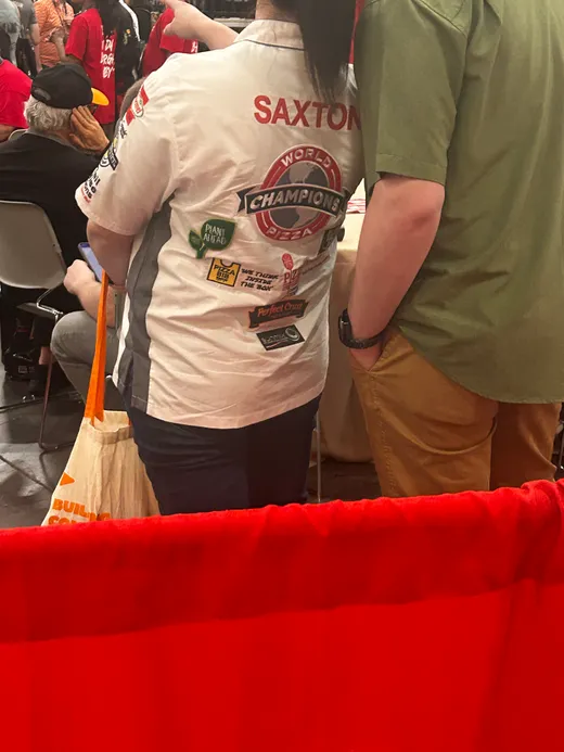 Two pizza people in a back-slapping hug near the competition curtains