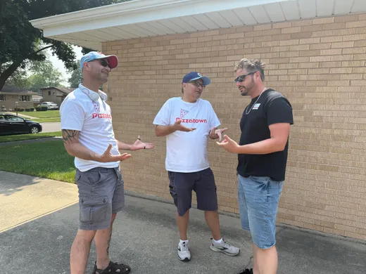 Three slice scouts mid-debate outside a suburban pizzeria