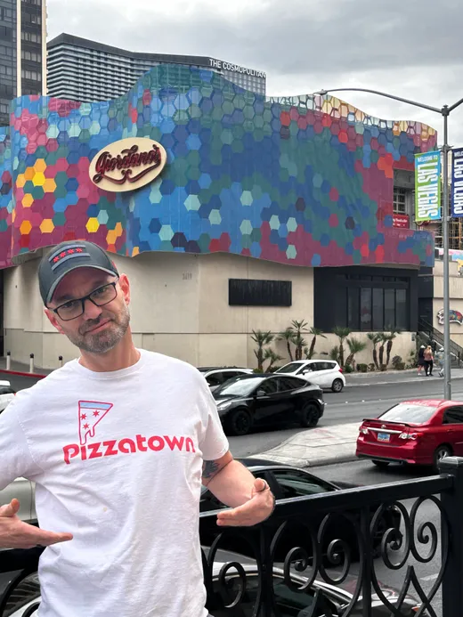A slice scout in a Pizzatown tee in front of the Giordano's mural on the Las Vegas Strip