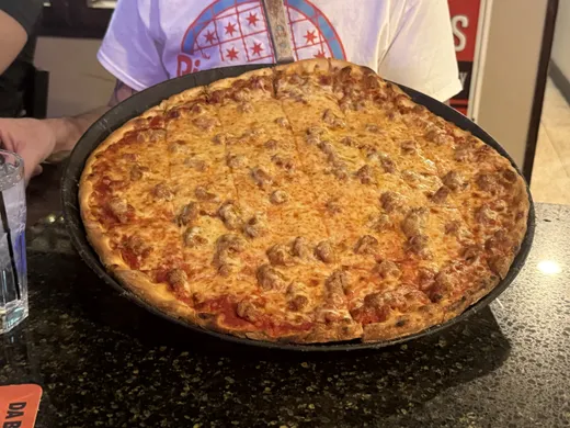 A sausage and mushroom tavern pie on a dark pan at Q's, cut and ready