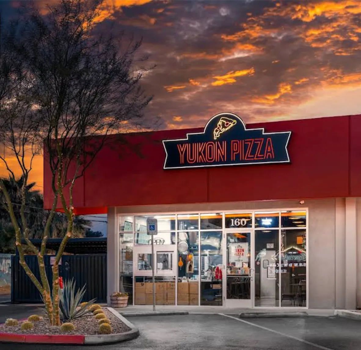 Yukon Pizza storefront in the Las Vegas Arts District under a blazing orange sunset sky